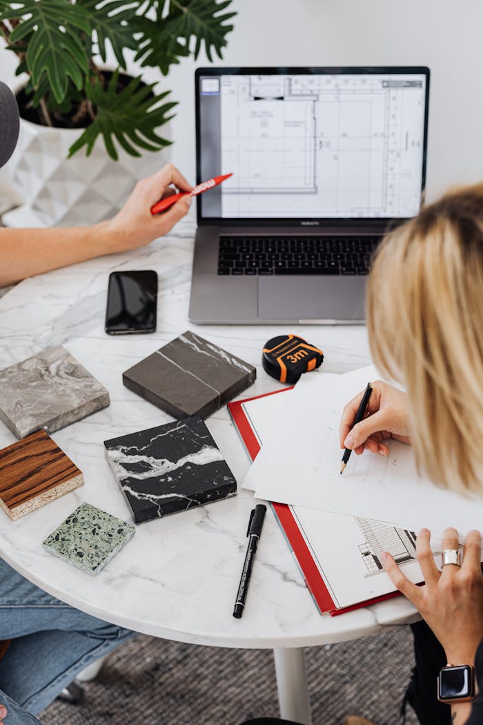 Creative professionals designing interior spaces with laptop and material samples at a modern work table.